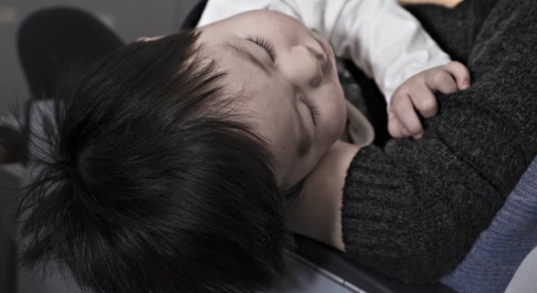 Kid lying on lap with fever at daycare