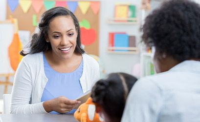 Teacher smiling at a child in a classroom setting, illustrating enhanced engagement.
