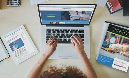 Person working on a laptop with documents and a coffee cup, illustrating how to enable and turn on features for better time management.