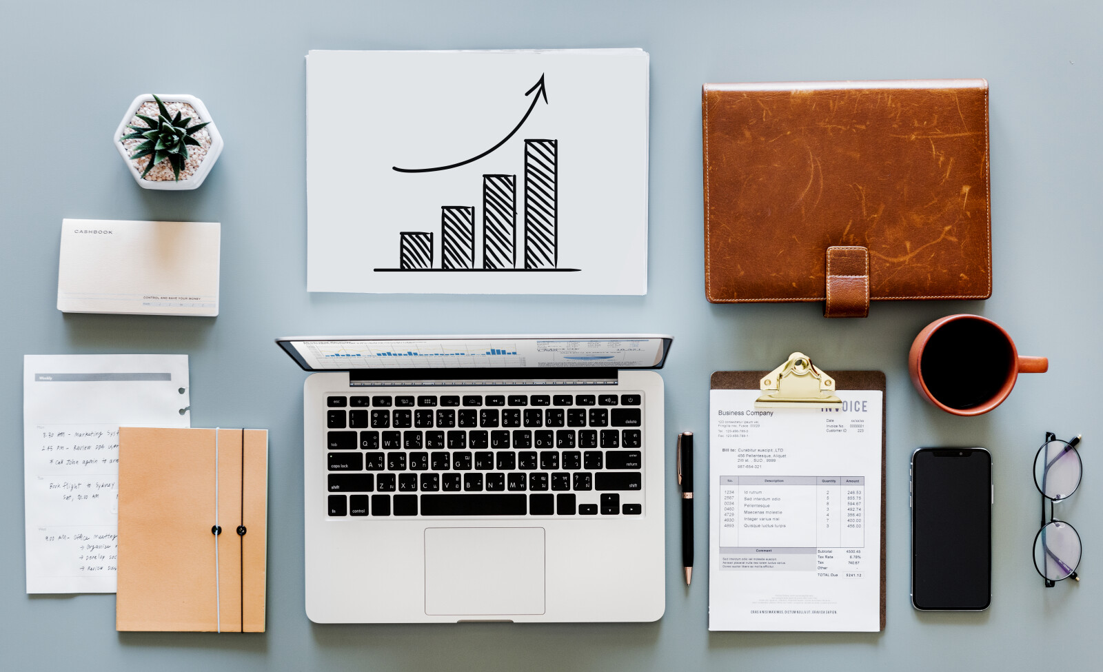 Photo of a bookkeeper's desk including a laptop, graphs, and notes on how to set up online payments for Catholic schools